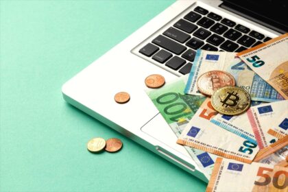 Banknoty i monety na laptopie jako symbol zarabiania na forex